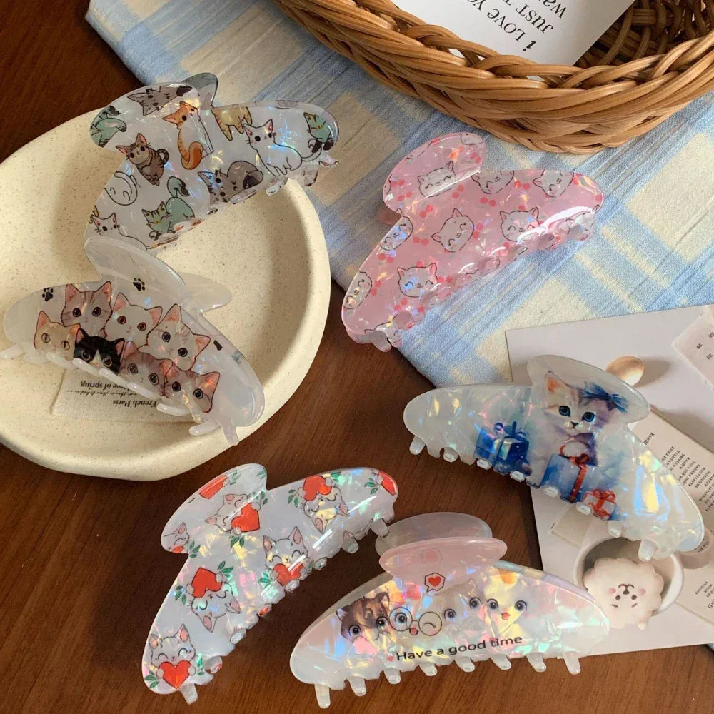 Several cat-themed claw clips displayed on a plate and a checkered cloth.