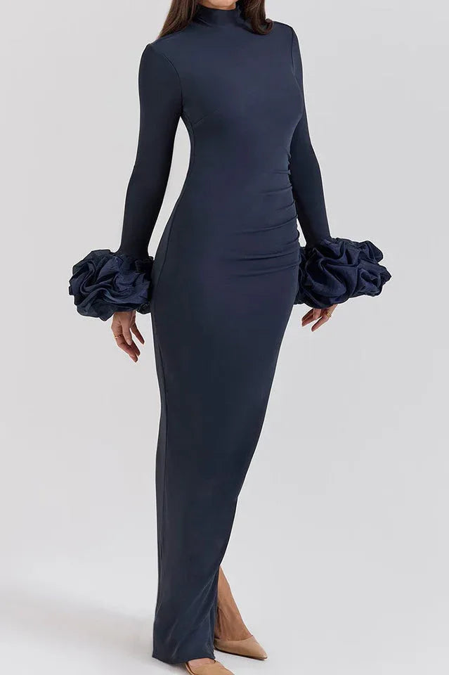 Side view of a navy blue long-sleeved column gown with a high slit and ruffled cuffs.