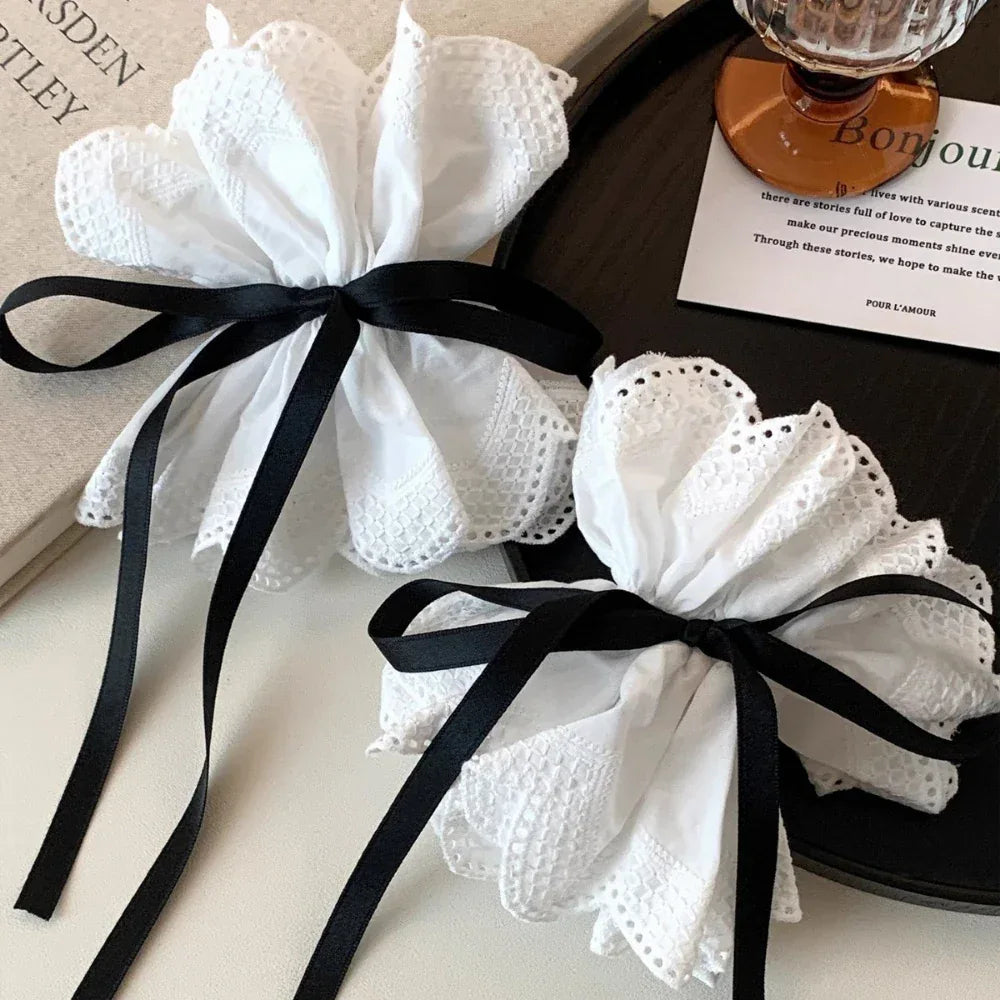 two white lace hair accessories tied with black ribbons