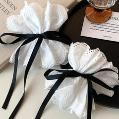 two white lace hair accessories tied with black ribbons