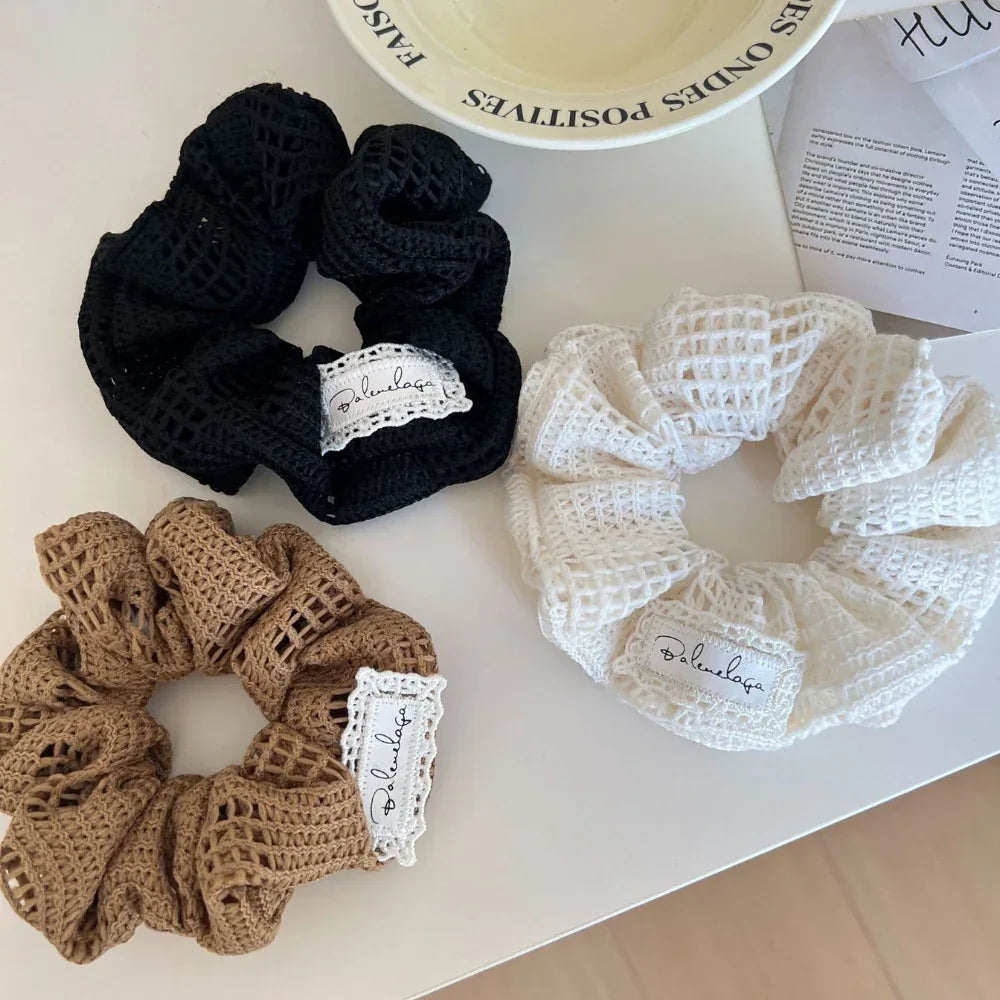 A collection of black, brown, and white crocheted scrunchies on a white table