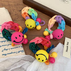 Several cheerful braided hair ties featuring smiley face charms and colorful beads, arranged on a wooden surface.