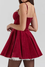 Back view of a woman in a red velvet mini dress with a zipper closure.