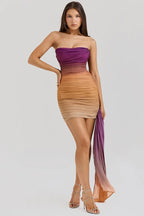 Woman wearing a strapless ombre ruched mini dress with a draped accent, front view