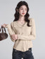 Woman wearing a beige ribbed knit cardigan with lace trim and a V-neck, holding a brown handbag.