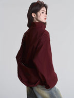 Back view of a woman in a maroon bomber jacket with a crossbody bag