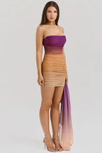 Woman wearing a strapless ombre ruched mini dress with a draped accent, side view