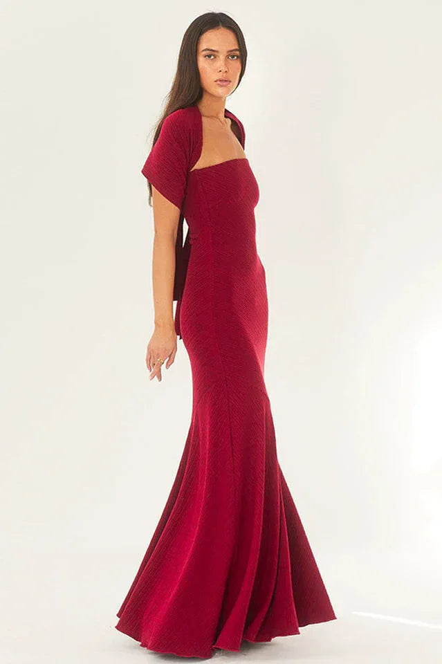 Woman wearing a red strapless mermaid gown with a scarf styled as a shawl over her shoulders