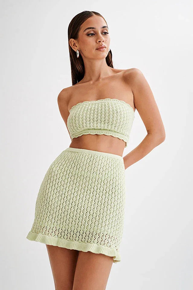 Woman wearing a light green crocheted tube top and mini skirt, front view Main image