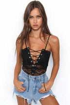 Woman wearing a black lace crop top with a lace-up front and denim shorts.