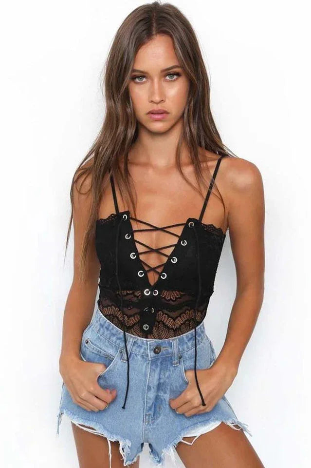 Woman wearing a black lace crop top with a lace-up front and denim shorts.