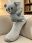 Close-up of a grey crew sock with a 3D koala character attached to the side.