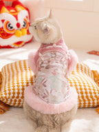 Rear view of a light-colored cat wearing a pink traditional Chinese-style vest with floral embroidery and pink faux fur trim.