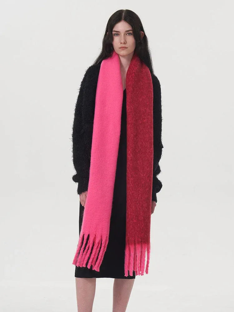 Front view of a woman wearing a black sweater and a two-toned pink and red scarf.
