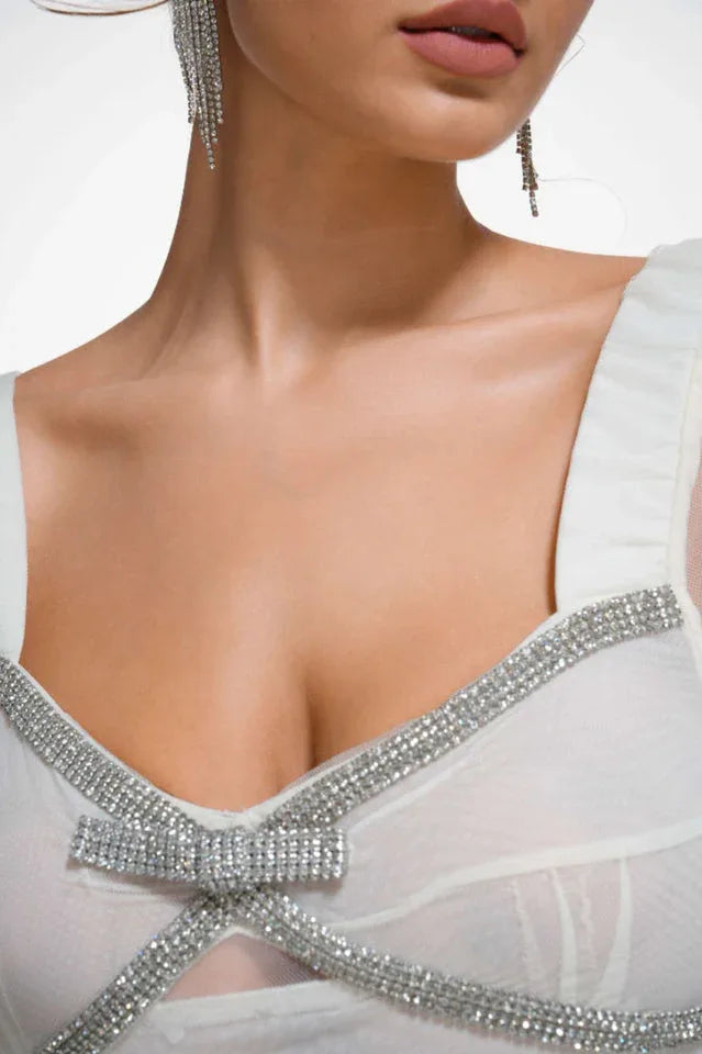 Close-up of the neckline of a white tiered tulle gown with crystal embellishments and a bow detail