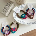 A flat lay of crocheted flower hair ties on a white plate and a table.