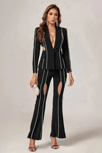 Woman in a black suit with cut-out details and decorative trim, holding a clutch.