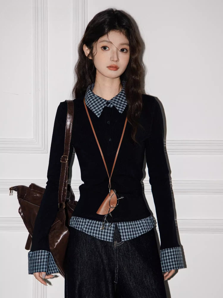 Full-body shot of a model in a layered black top with checkered accents, dark wash wide-leg jeans, and a brown shoulder bag.