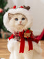 White cat wearing a festive red plaid cape with reindeer antlers and faux fur trim.
