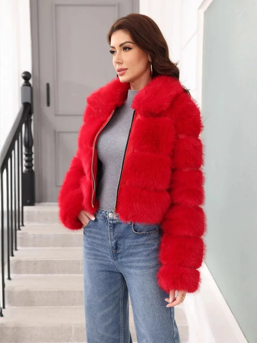 Woman wearing a red faux fur cropped jacket with a grey turtleneck and blue jeans, standing on stairs and looking to the side.