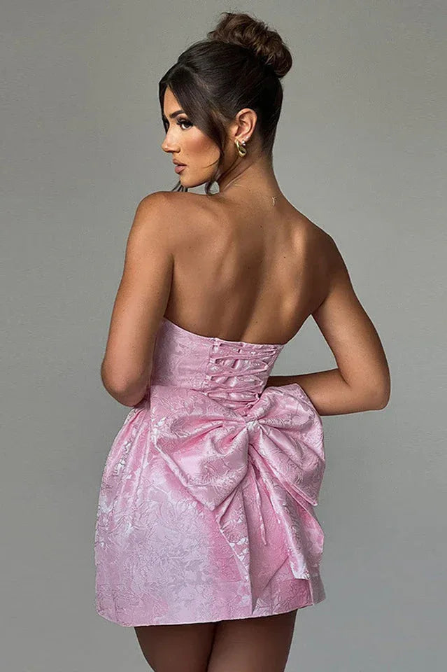 Back view of a pink strapless dress with corset detailing and a large bow.