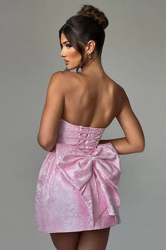 Back view of a pink strapless dress with corset detailing and a large bow.