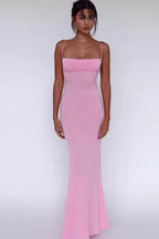 Woman wearing a pink maxi dress with spaghetti straps and a square neckline.