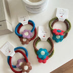 Various crocheted flower hair ties arranged on a white surface.