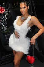 Woman in a white fluffy mini dress posing next to a car.