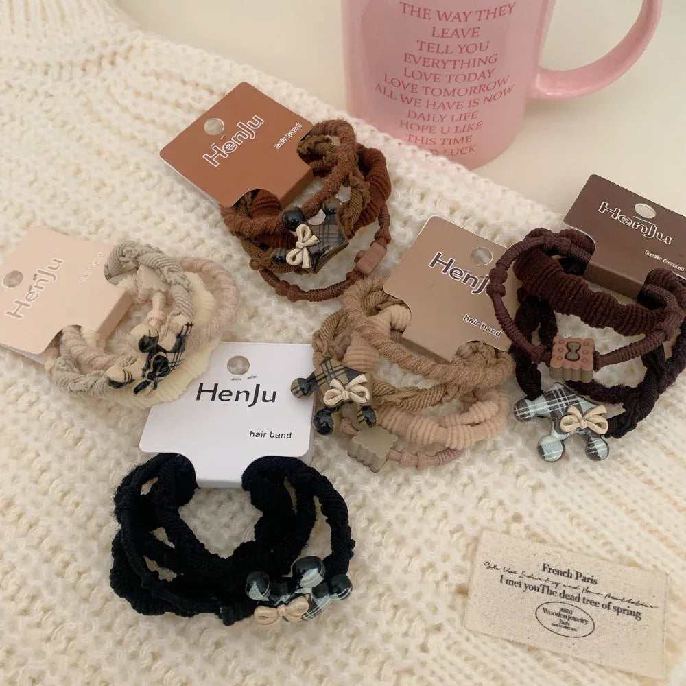 Assortment of Henju hair ties, including black, brown, and beige sets, with plaid and bow embellishments