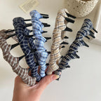 A collection of plaid fabric-wrapped headbands with black interlocking teeth in various colors