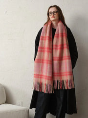 Woman wearing a black coat and a pink plaid scarf, showing the full length of the scarf.