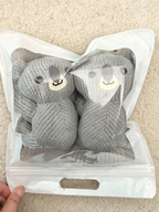 A pair of grey crew socks with 3D koala characters packaged in a clear plastic bag.