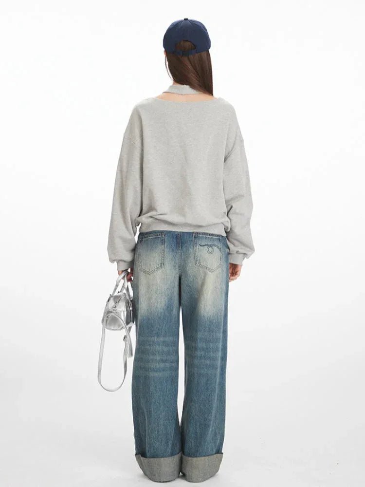 Model wearing a grey graphic print sweatshirt and wide-leg jeans, back view