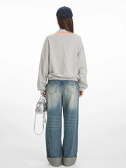 Model wearing a grey graphic print sweatshirt and wide-leg jeans, back view