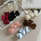 Assortment of bow-shaped hair clips displayed on a neutral surface, some arranged in a white basket.