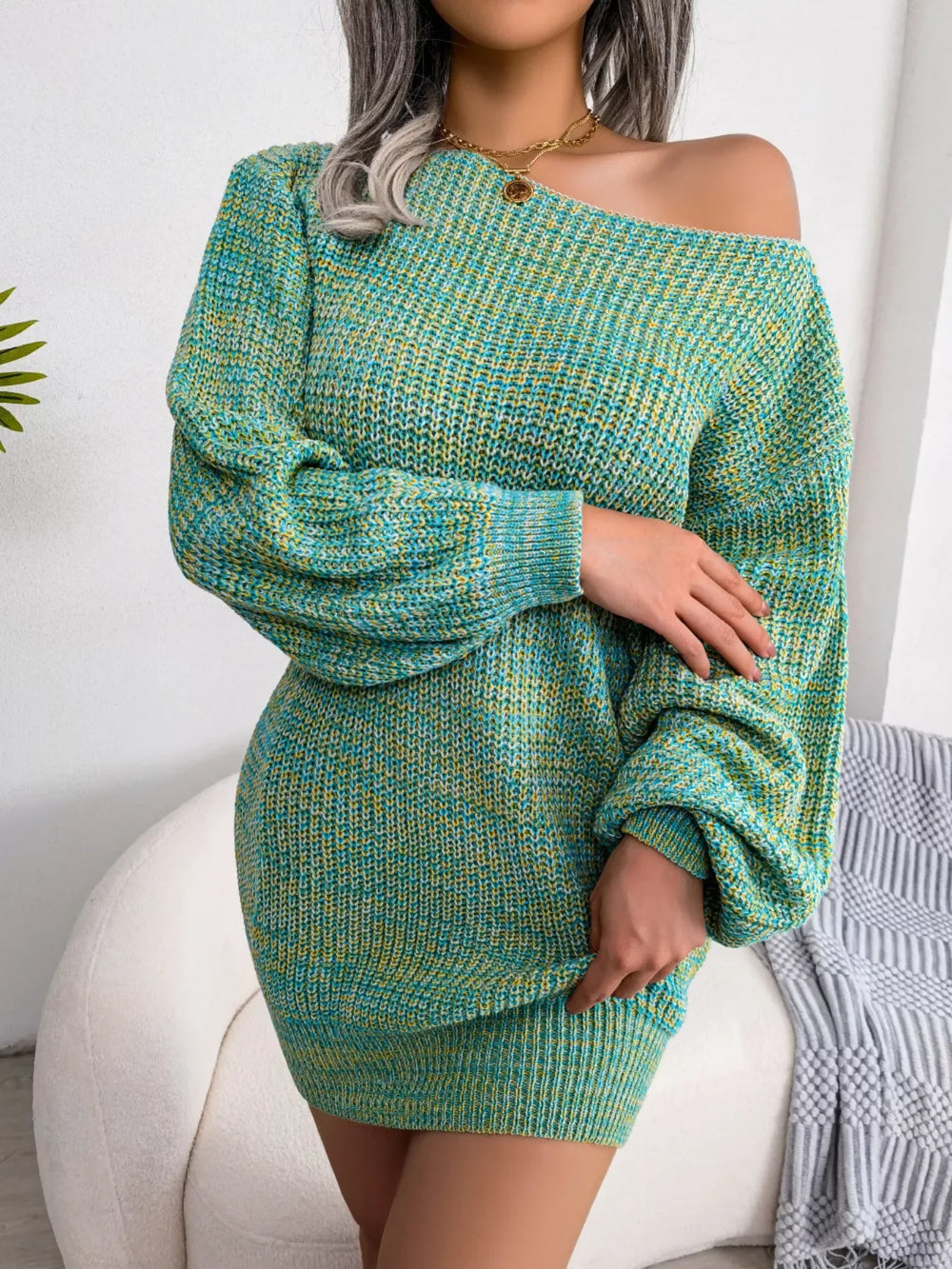 Woman wearing a green and yellow marled knit off-the-shoulder mini dress with long balloon sleeves, arms crossed.