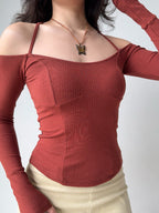 Detail shot of the rust-colored ribbed knit top, highlighting the off-the-shoulder sleeves and the halter neckline.