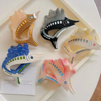 Top-down view of five colorful marlin hair clips on a white tray
