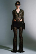 Model wearing a black lace bodysuit with flared pants and a mini skirt overlay.