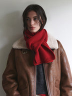 A woman wearing a brown aviator jacket with a red scarf around her neck.