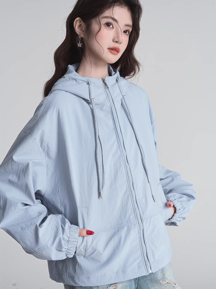 Woman with hands in the pockets of a light blue hooded jacket, showcasing the relaxed fit.