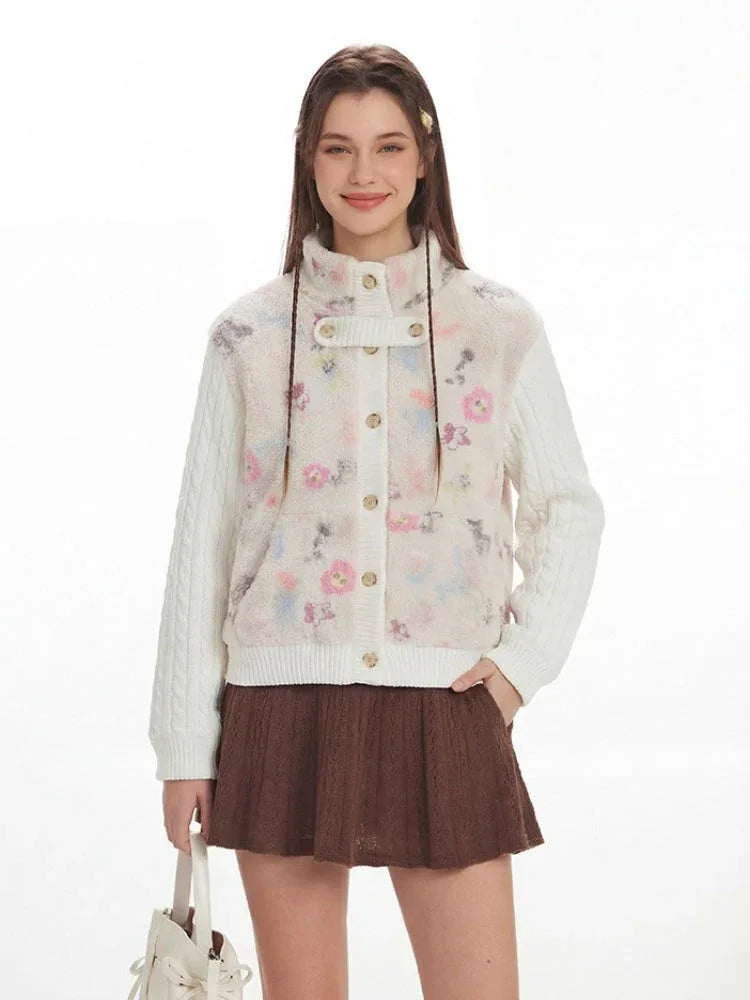 Front view of a woman smiling and posing in a floral print fleece bomber jacket with cable knit sleeves and a brown pleated skirt.