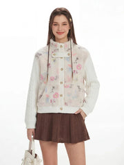 Front view of a woman smiling and posing in a floral print fleece bomber jacket with cable knit sleeves and a brown pleated skirt.