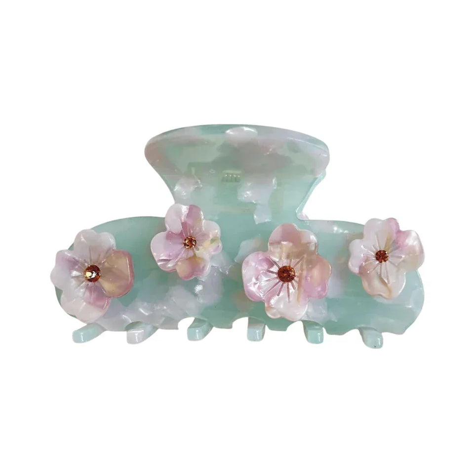 A mint green acetate claw hair clip adorned with four delicate pink and white flowers, each with a small brown gem in the center. Main image
