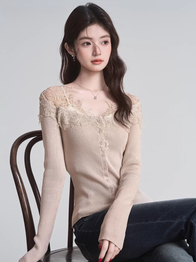 Woman sitting on a chair wearing a beige ribbed knit cardigan with lace trim and a v-neck, paired with dark wash jeans.