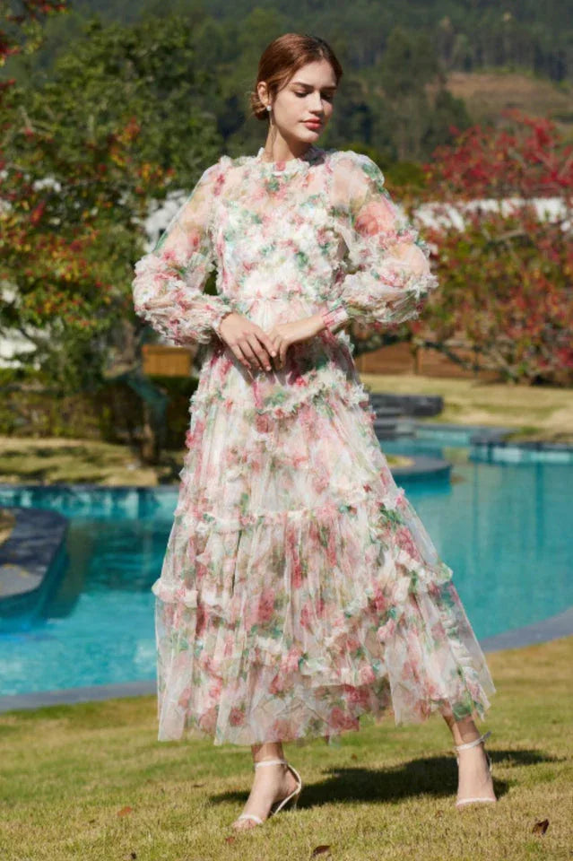 Full-length shot of a woman in a floral print chiffon gown with tiered ruffles and bishop sleeves.