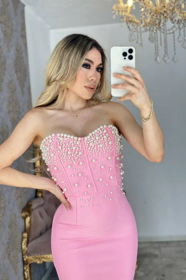 Woman in a pink strapless pearl-embellished mermaid gown taking a mirror selfie.