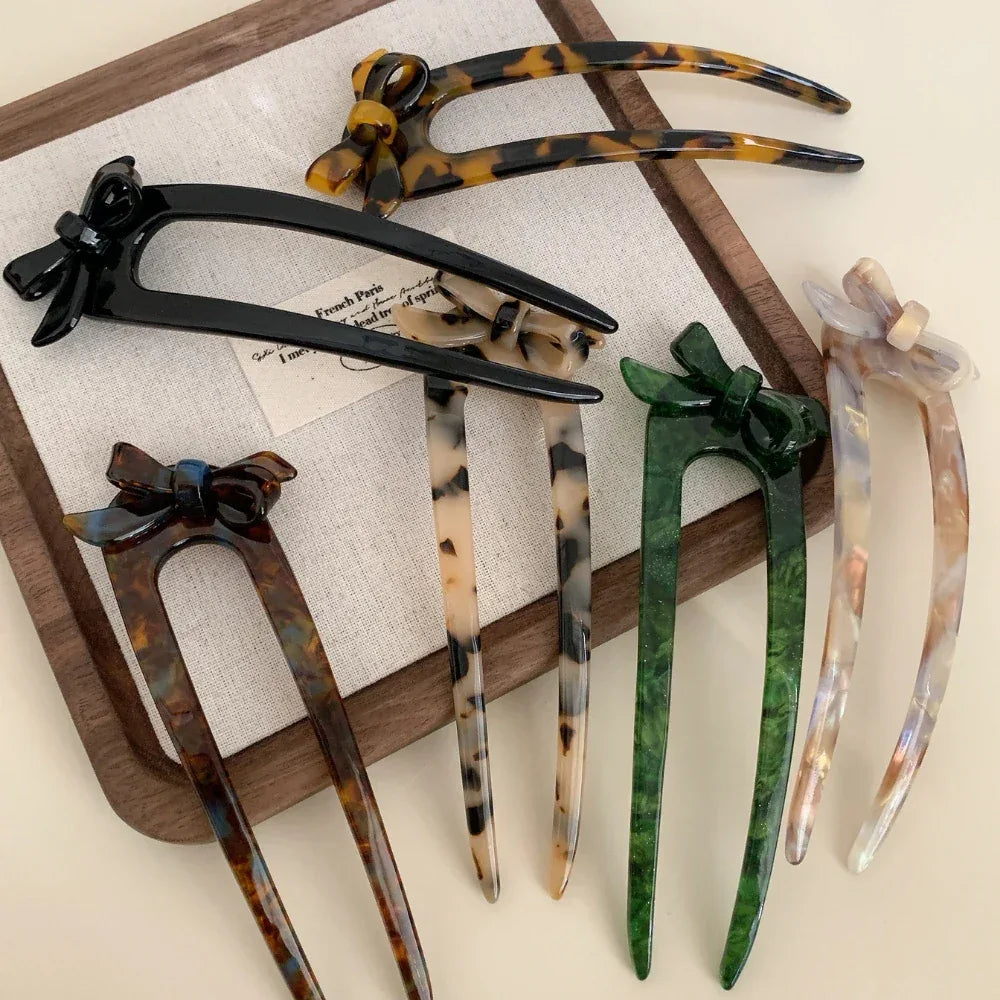 A variety of decorative hair forks with bow embellishments presented on a tray and a book