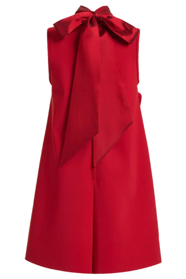 Close-up back view of a red sleeveless A-line mini dress with a large red bow detail.